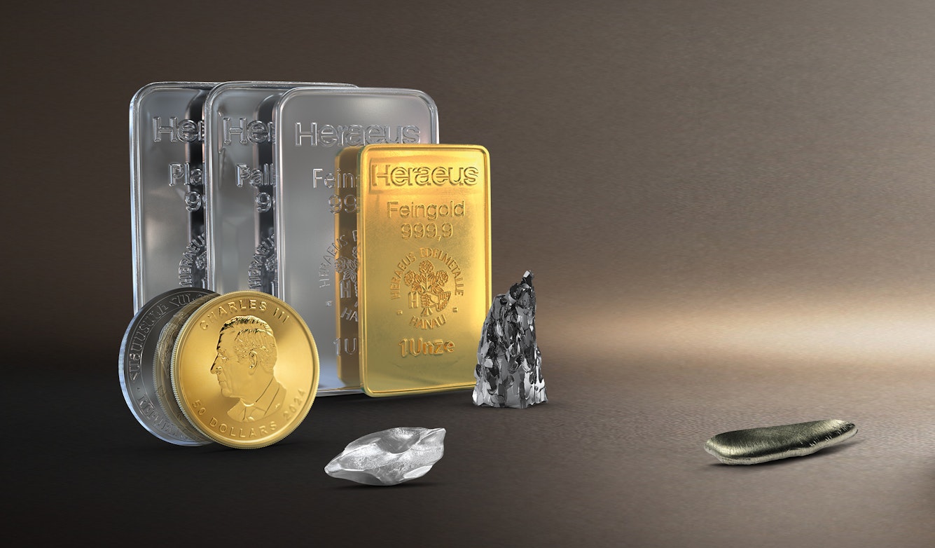 Vor einem erdfarbenen Hintergrund sind Edelmetallbarren, eine Gold- und Silbermünze Technologiemetalle und Seltene Erden abgebildet. Sparen auch Sie in Anlagemetalle mit den Sparplänen von Golden Gates.