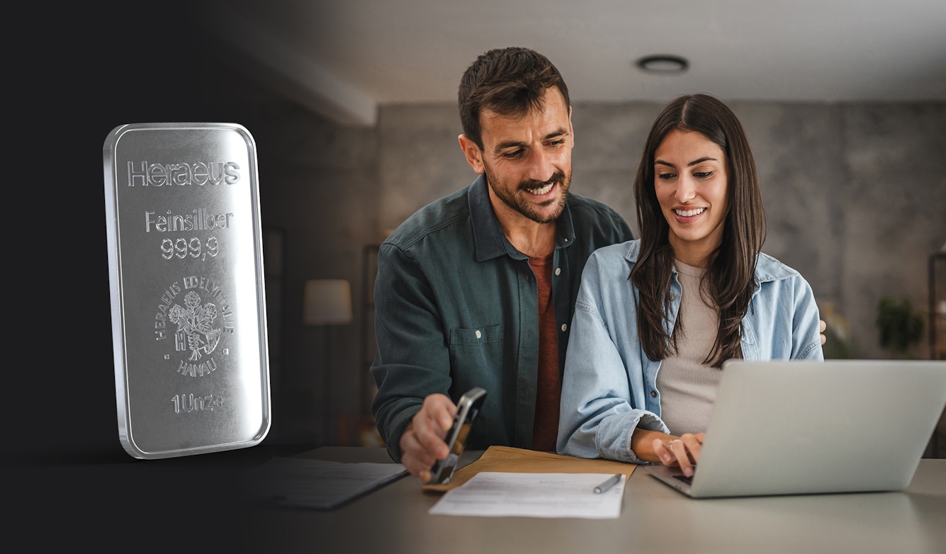 Ein Paar, das in einem erdfarbenen Wohnzimmer am Tisch vor einem Laptop sitzt, sieht freudig auf den Sparplanvertrag, welchen sie bei Golden Gates abgeschlossen haben. Legen auch Sie Ihr Geld richtig an und sparen Sie in Anlagemetalle mit Golden Gates.