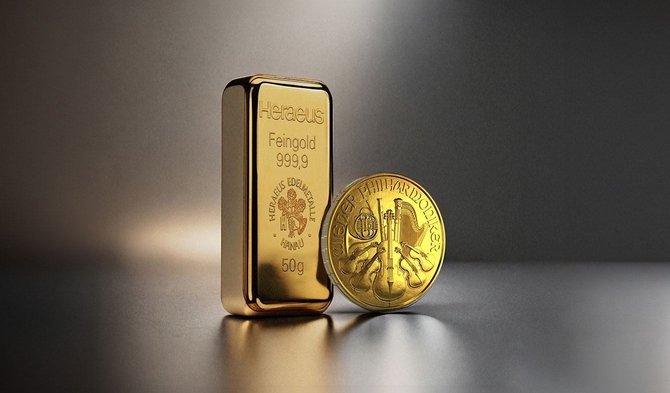 Vor einem dunklen Hintergrund stehen ein Goldbarren und eine Wiener Philharmoniker Goldmünze. Edelmetall-Sparpläne von Golden Gates.