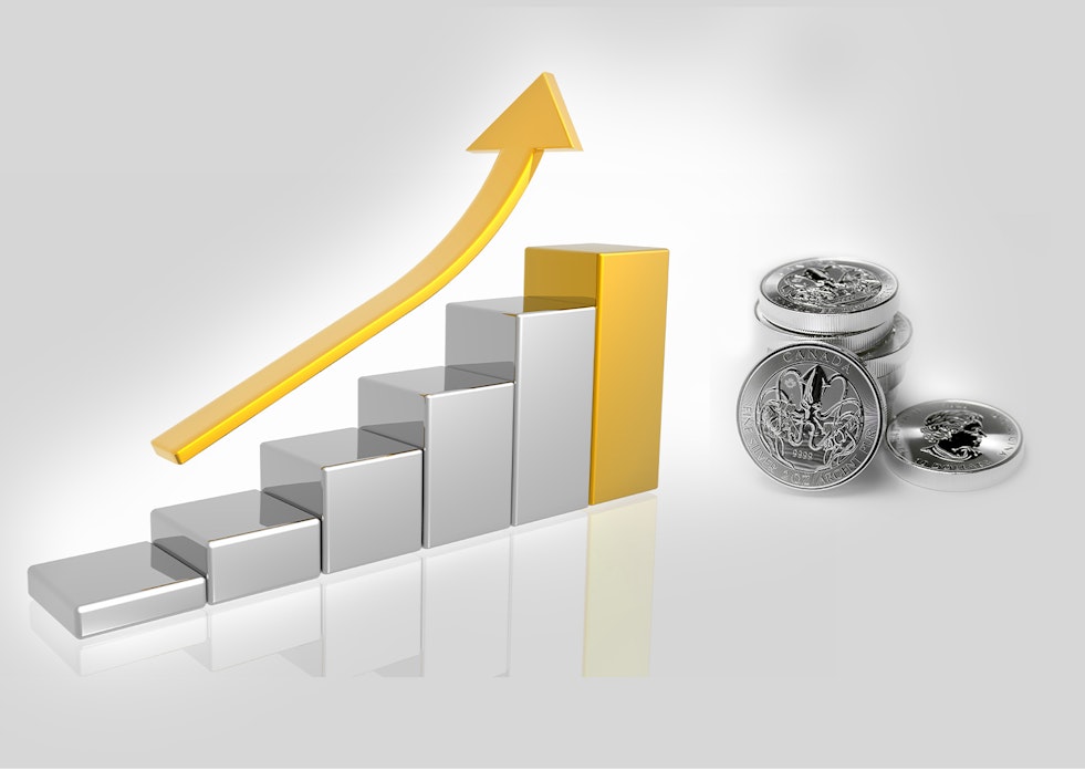 Auf dem Bild ist ein steigendes Balkendiagramm, über welchem ein goldener Pfeil schwebt, zu sehen. Die stellt die steigende Entwicklung von Silber dar. Daneben sind Silbermünzen abgebildet. Sparen Sie in Silber mit den Sparplänen oder der Einmalanlage von Golden Gates.