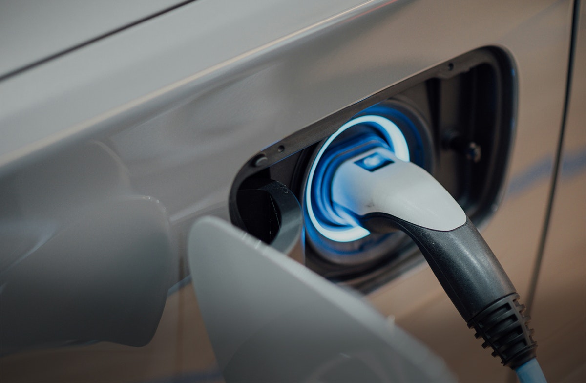 Automobil- und Energietechnik Auf diesem Bild ist der Ausschnitt eines Autos an der Ladesäule zu sehen. In Anlagemetalle sparen mit den Sparplänen von Golden Gates.
