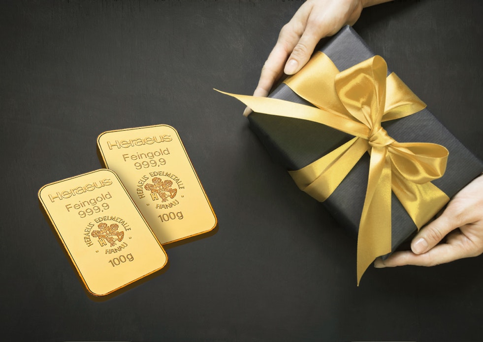 Auf einem schwarzen Untergrund liegt ein schwarz eingepacktes Geschenk mit goldener Schleife und daneben zwei Goldbarren. Gold für jeden Anlass: Hochzeit, Taufe, Schulanfang, Weihnachten, Geburtstag, mit Golden Gates.