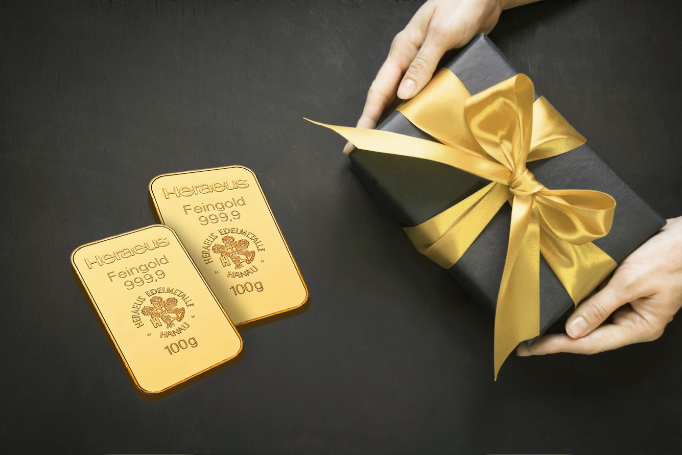 Auf einem schwarzen Untergrund liegt ein schwarz eingepacktes Geschenk mit goldener Schleife und daneben zwei Goldbarren. Gold für jeden Anlass: Hochzeit, Taufe, Schulanfang, Weihnachten, Geburtstag, mit Golden Gates.